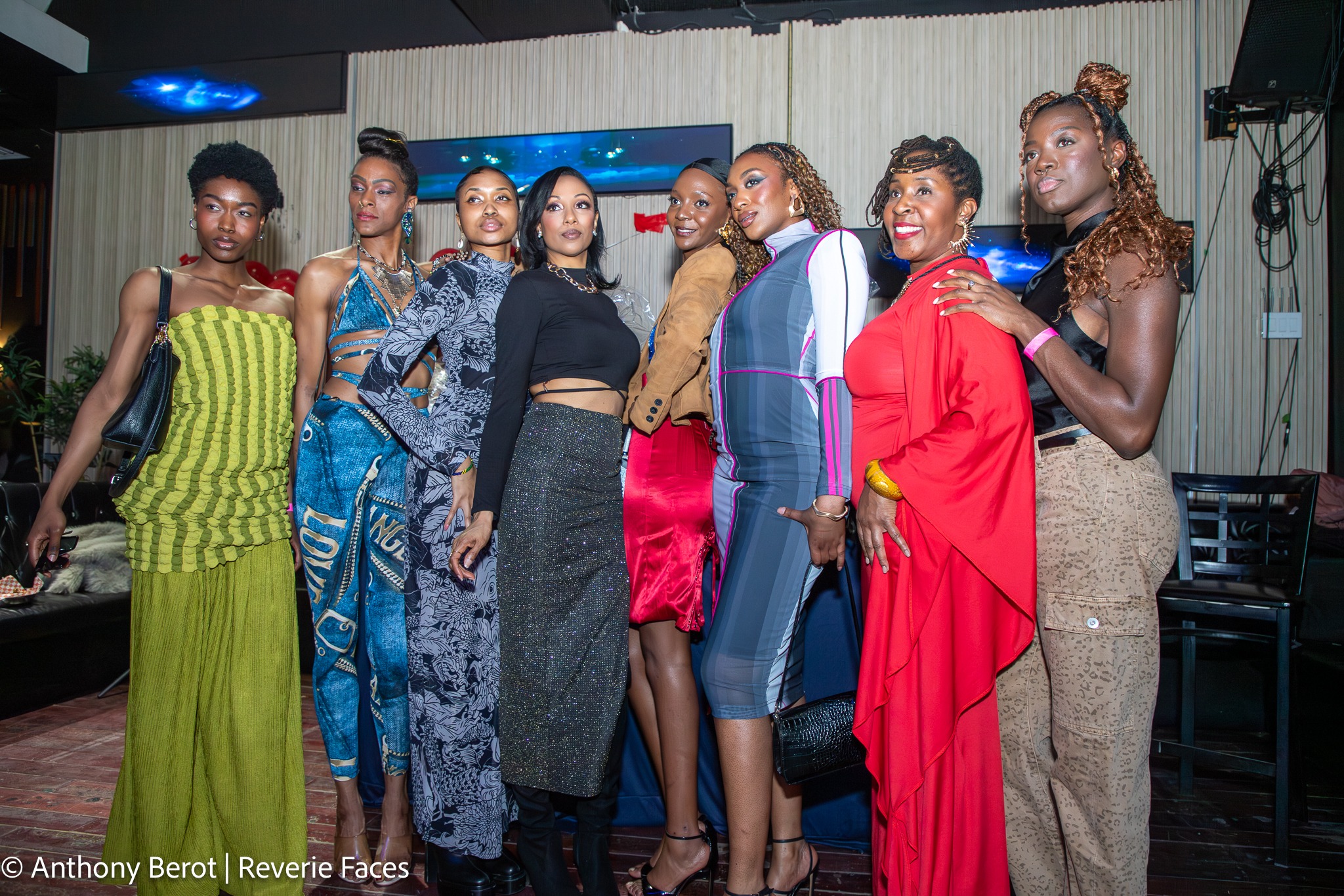 Eight people standing together in distinct outfits, with varied colours, patterns, silhouettes and accessories.